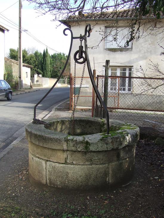 Génissac, un puits avec treuil, support et chaine de levage.